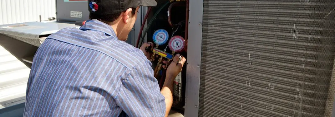 HVAC technician servicing a condenser unit in Highland Lakes
